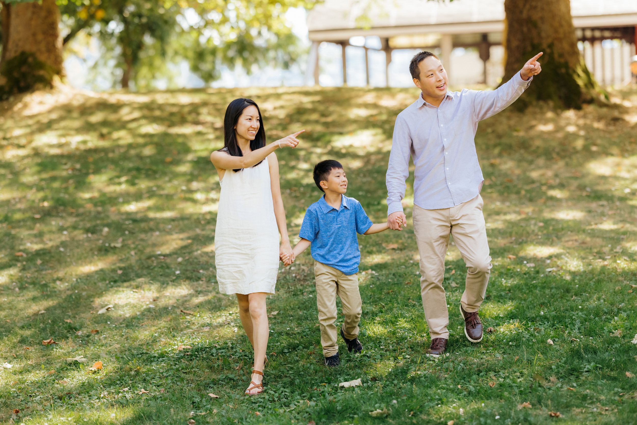A family walks together holding hands in a sunny park setting.