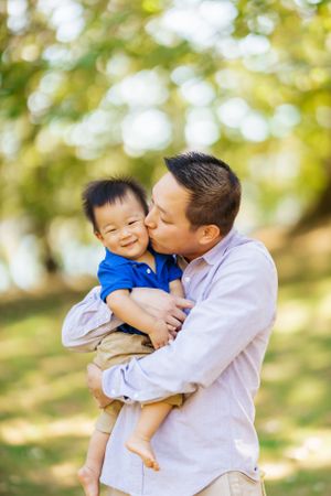 A tender moment shared between parent and child embracing outdoors with natural bokeh background.