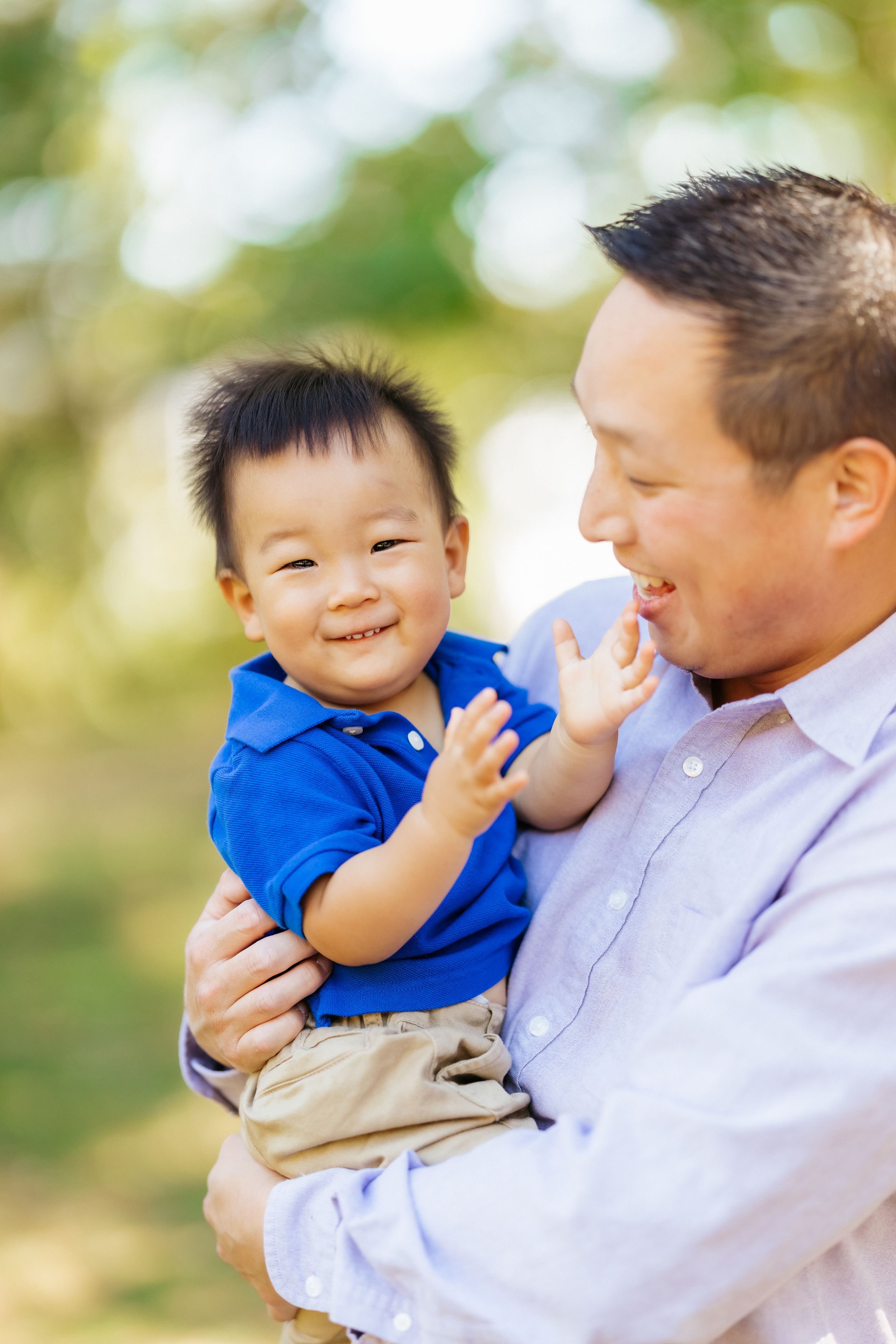 A playful moment captured between parent and child laughing together in an outdoor setting.