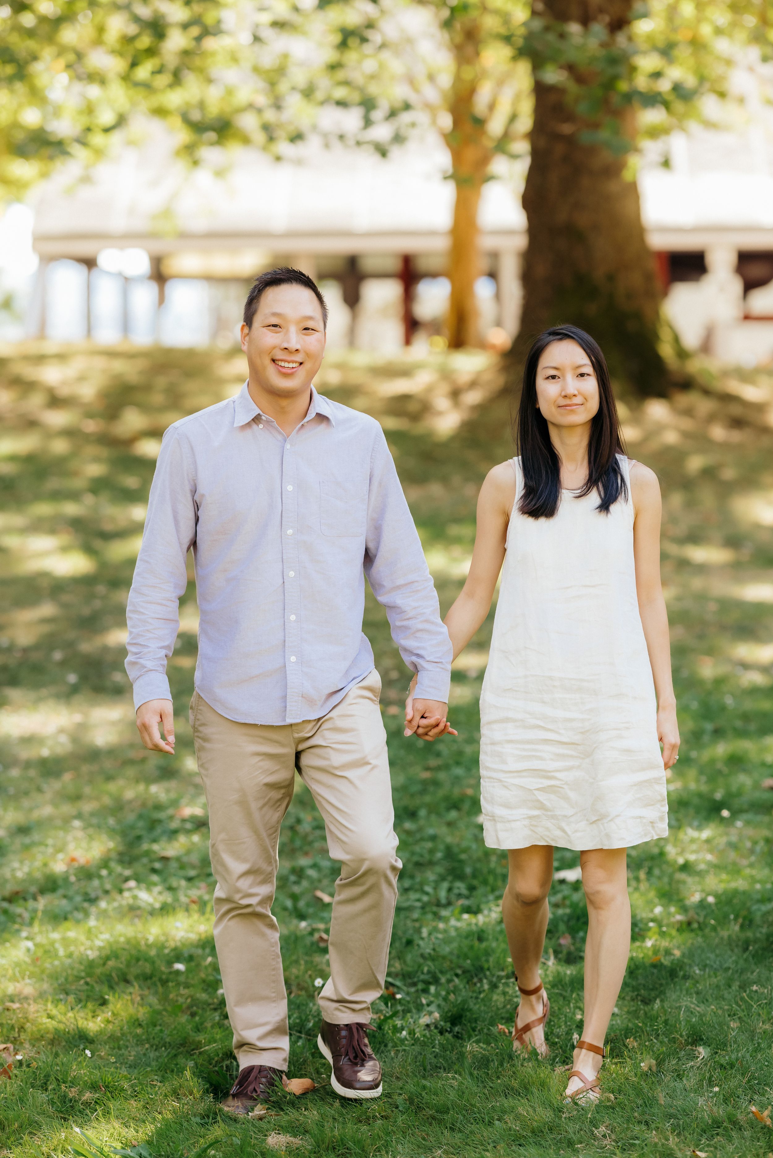 A couple walks hand in hand through a sunny park wearing coordinated casual outfits.