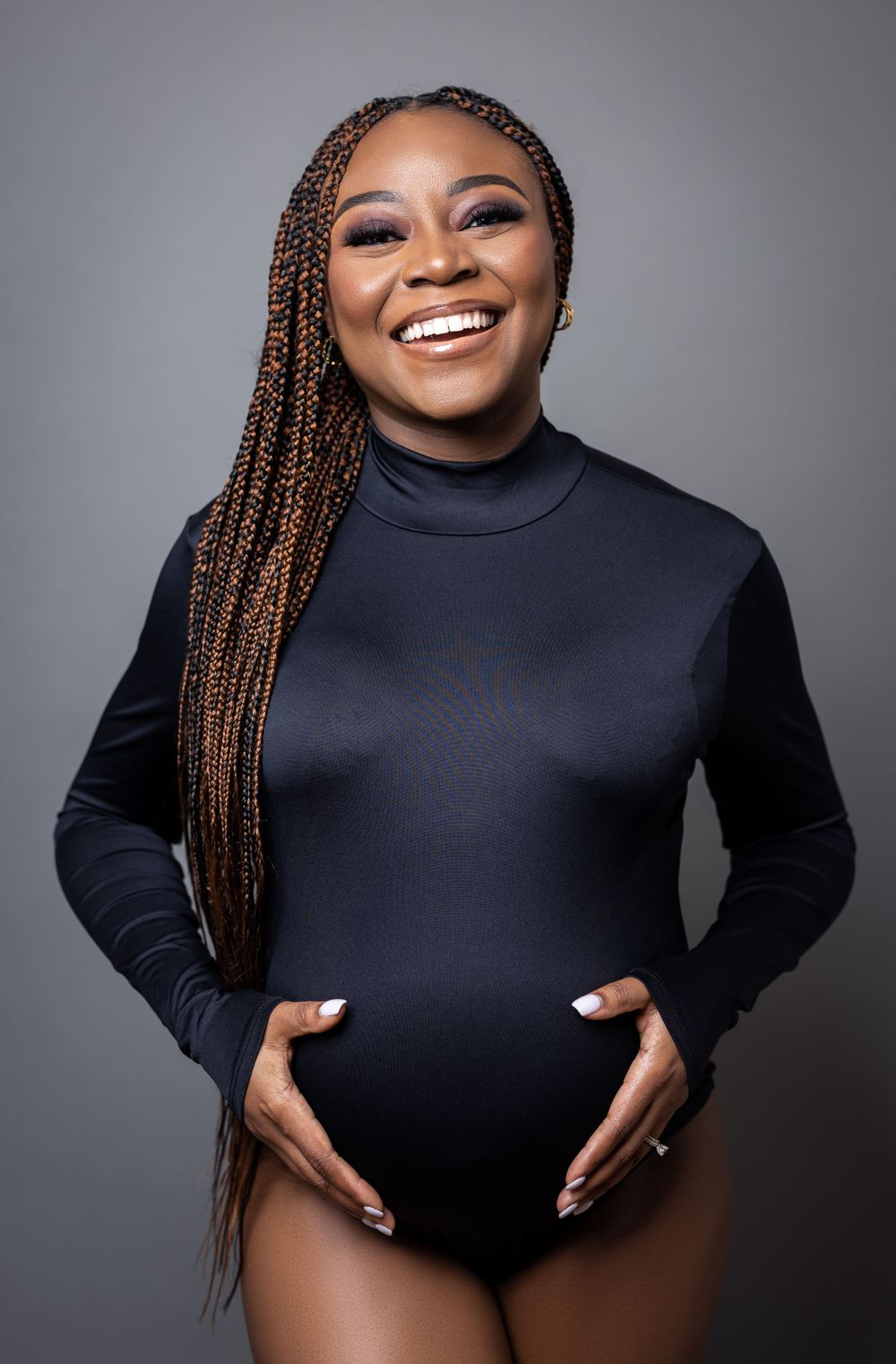 Professional maternity portrait in black bodysuit with long braided hair.