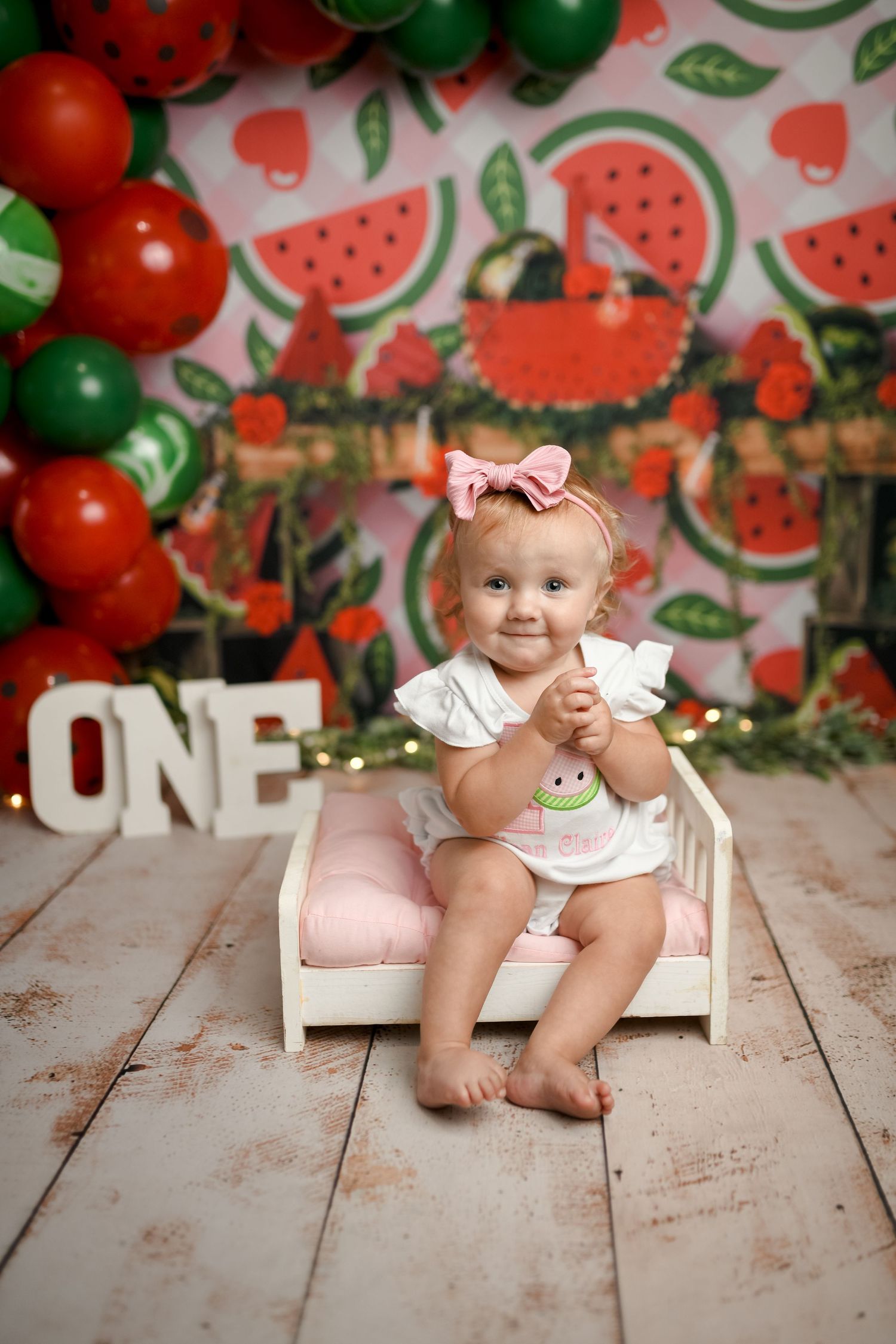 Watermelon themed photo setup with red and green decorations on wooden floor.