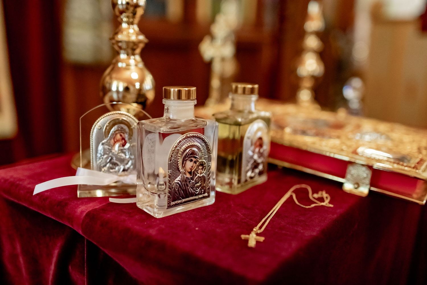 Holy water bottles and ceremonial keys displayed on red velvet cloth during religious ceremony.