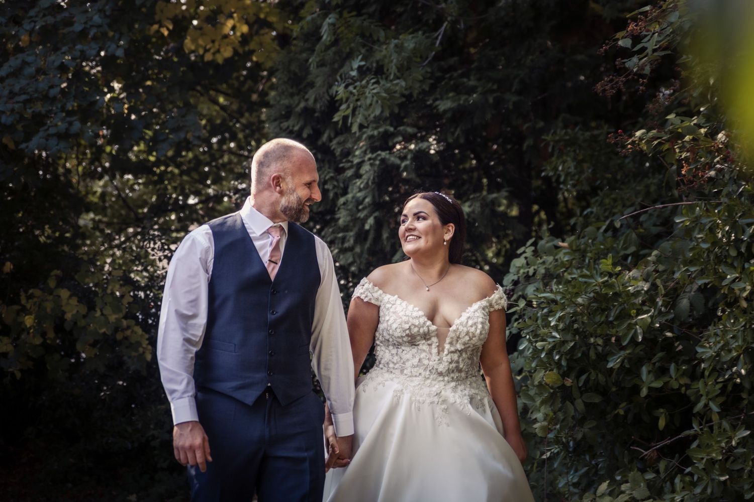 Wedding couple embracing in romantic garden setting with bokeh lighting effects.