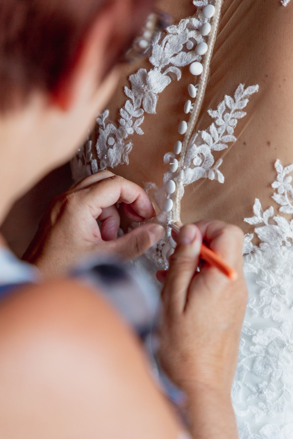 Close-up detail of delicate white lace and floral appliques on a wedding dress.