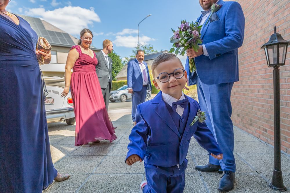Wedding party members in blue and coral attire gathered outside on a sunny day.