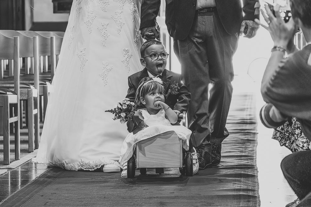 Black and white photo of small children on a wedding aisle with decorative white fabric.