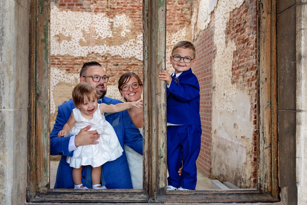 Children in bright blue outfits play in an old window frame.