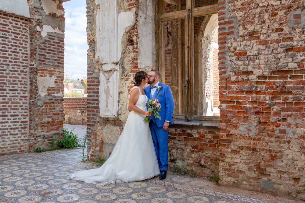 A couple shares a romantic moment against weathered brick walls during their wedding.
