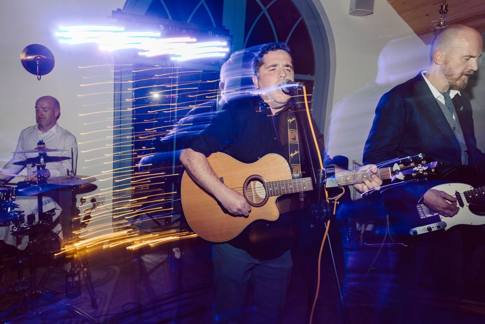 Band performs on stage with blue lighting and musical instruments at wedding reception.