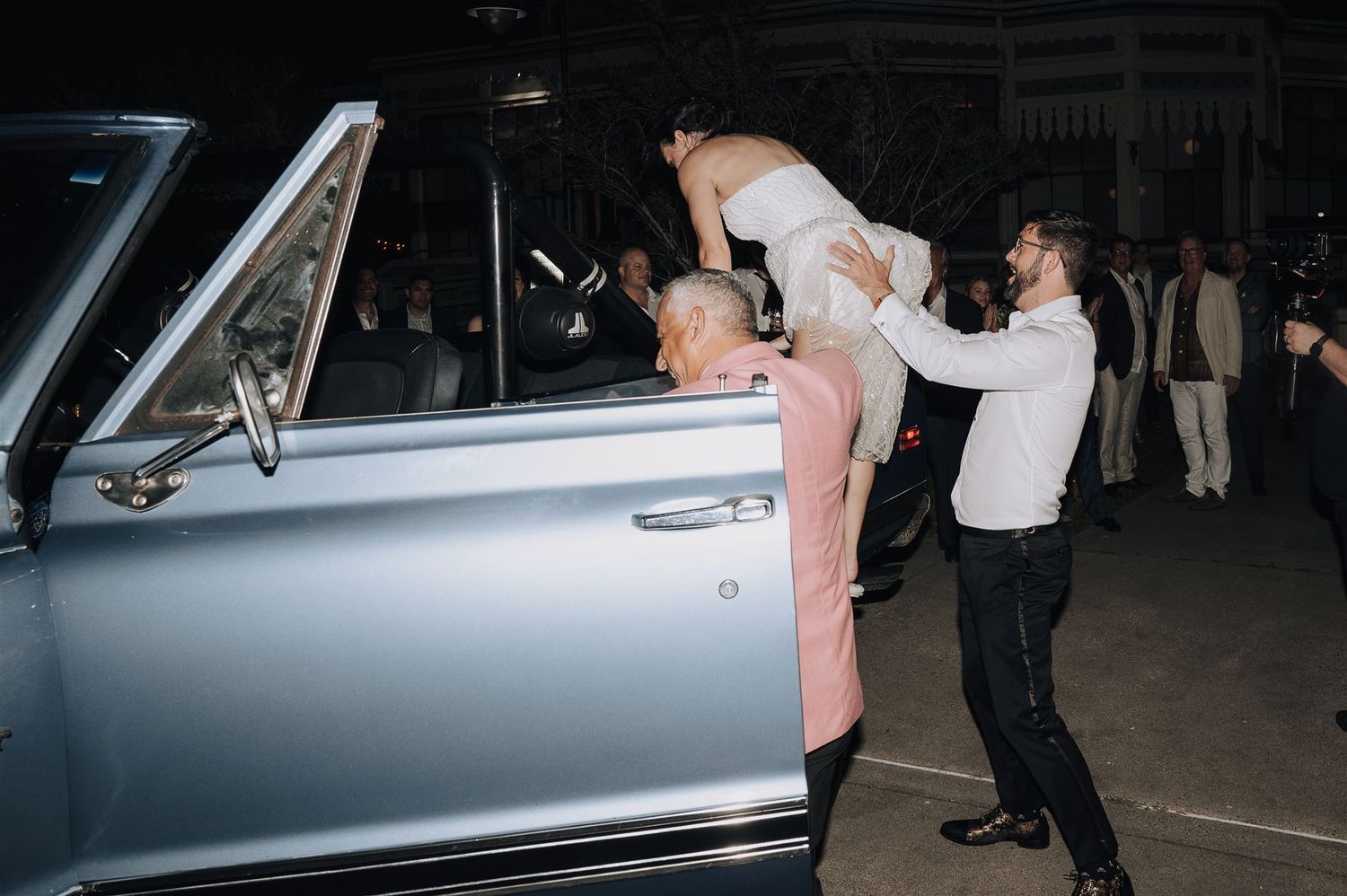 A classic silver vintage car serves as the getaway vehicle for the wedding couple.