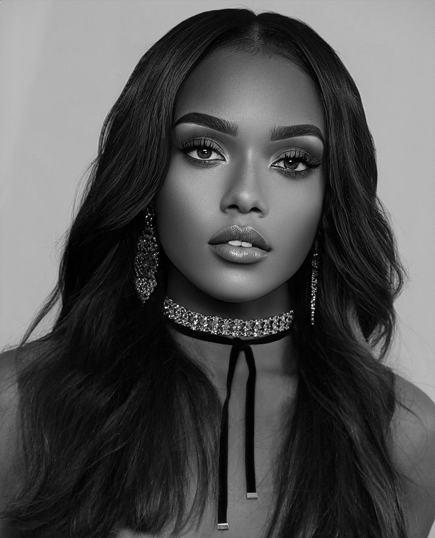 Stunning black and white portrait of woman with long hair, diamond choker and earrings, bold makeup.