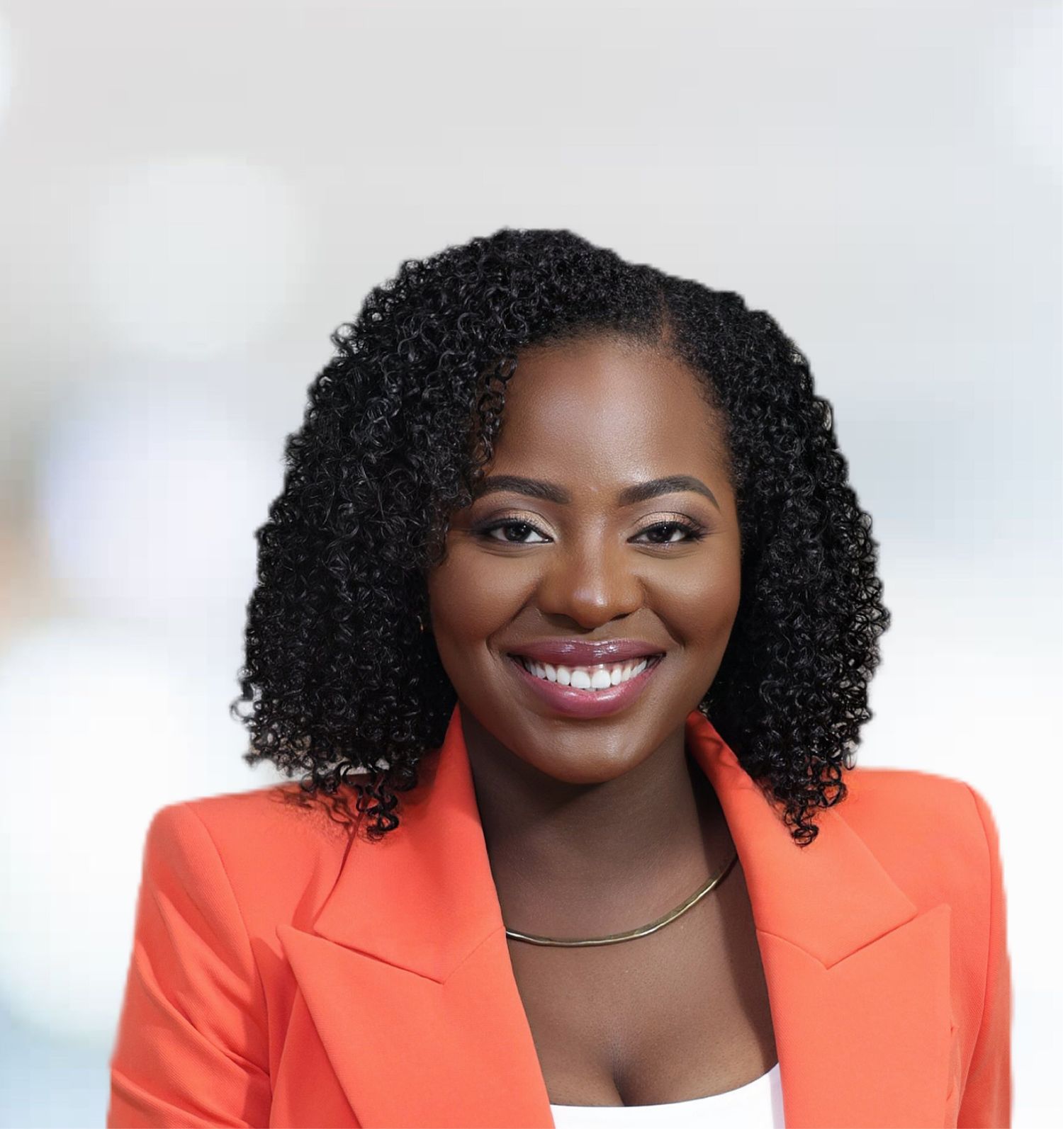 Smiling Black woman in orange blazer with curly hair posing for professional headshot.