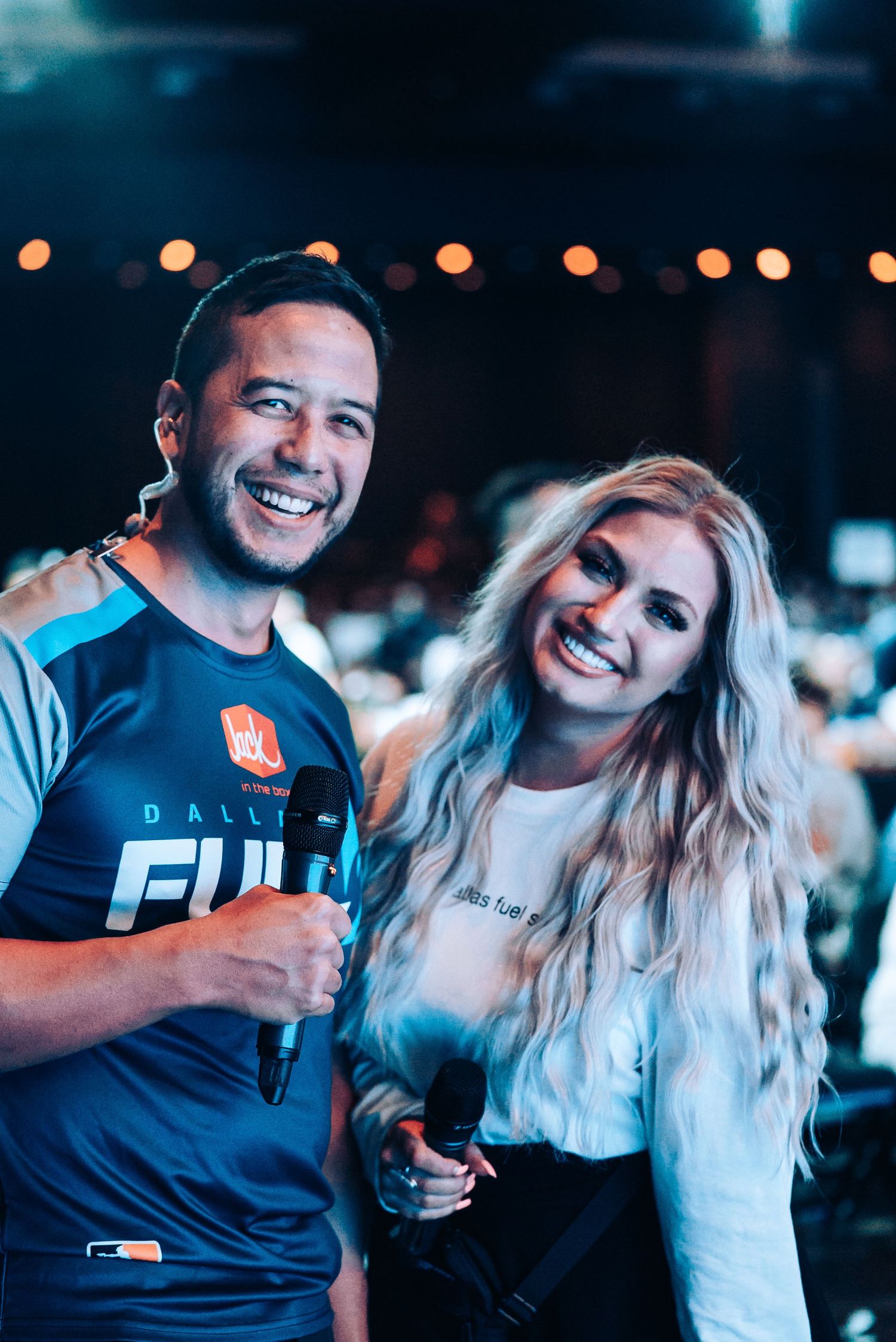 Two people enjoying drinks together at a nighttime event with bokeh lights in background.