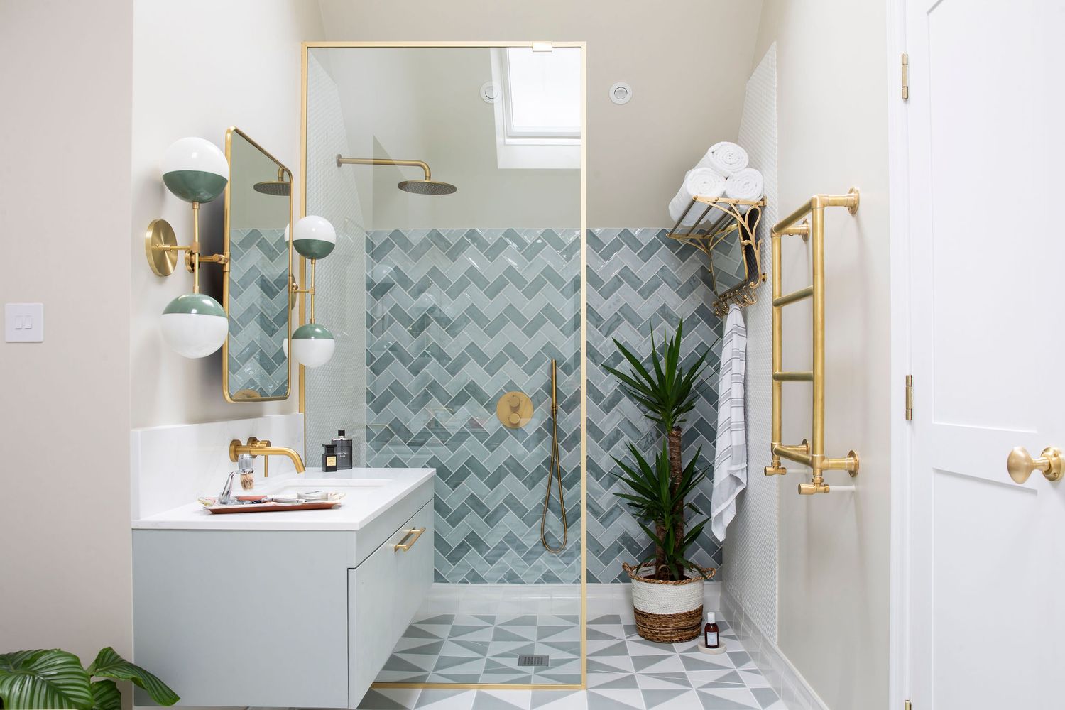 Modern bathroom with chevron tile, gold fixtures, and green plants showcases contemporary design elements.
