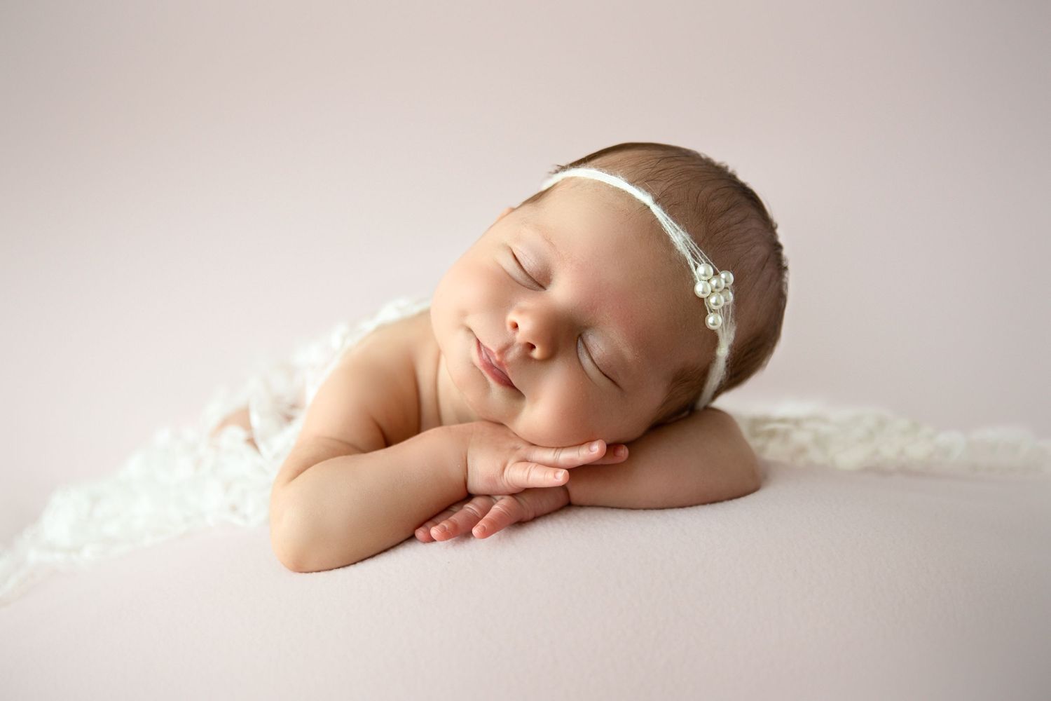 Prosessional newborn photography in Dubai showing baby posed chin on hands with neutral colours and soft textures