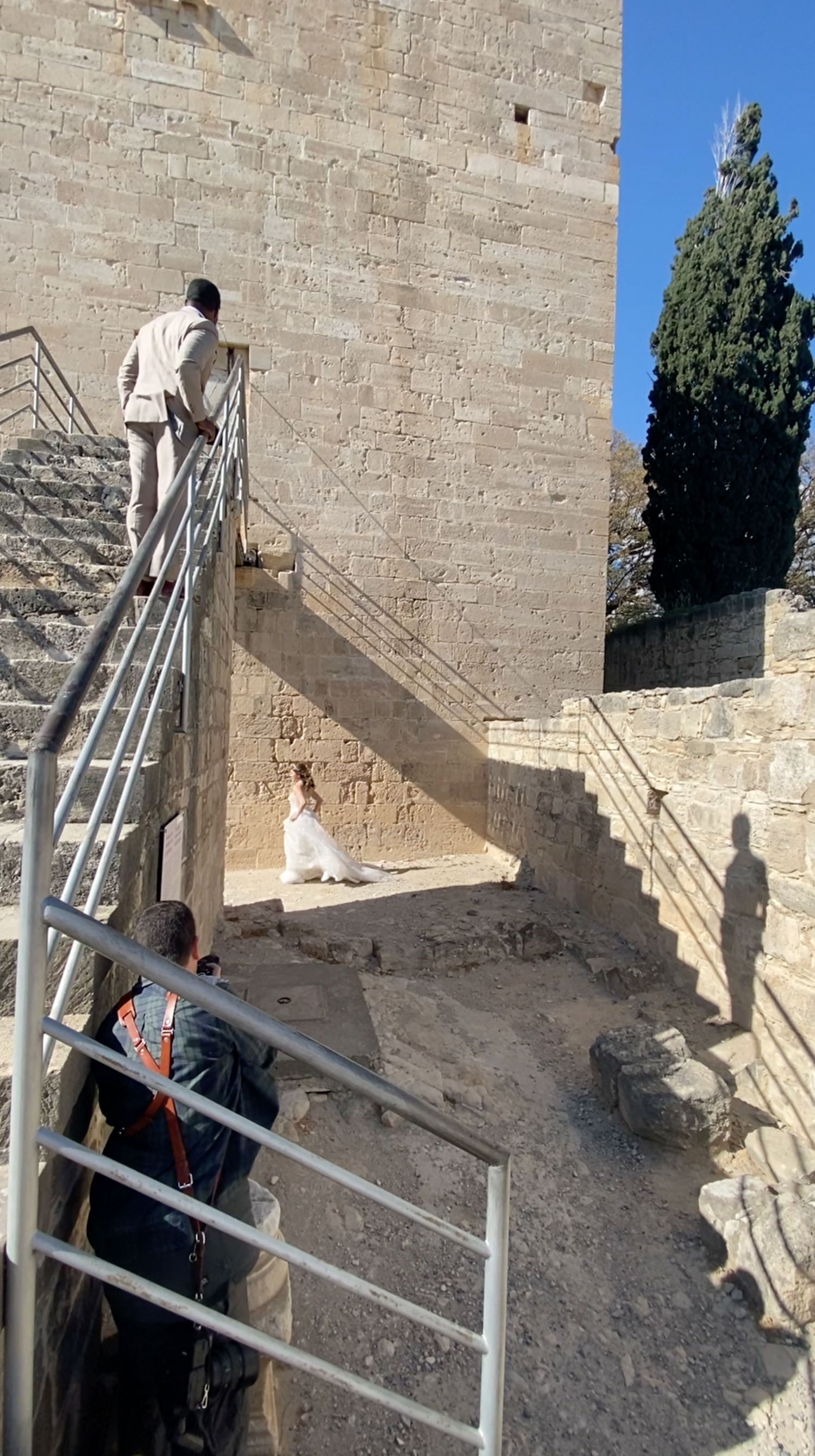 Workers installing metal railings along stone steps next to a brick wall outdoors.