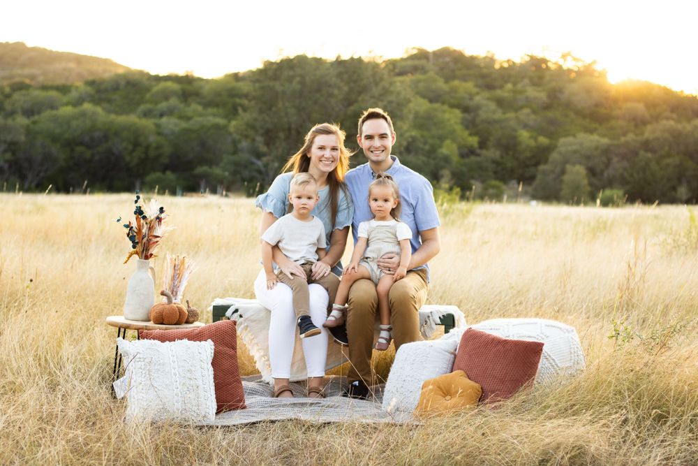 Family relaxes on a blanket in a sunny field during golden hour.