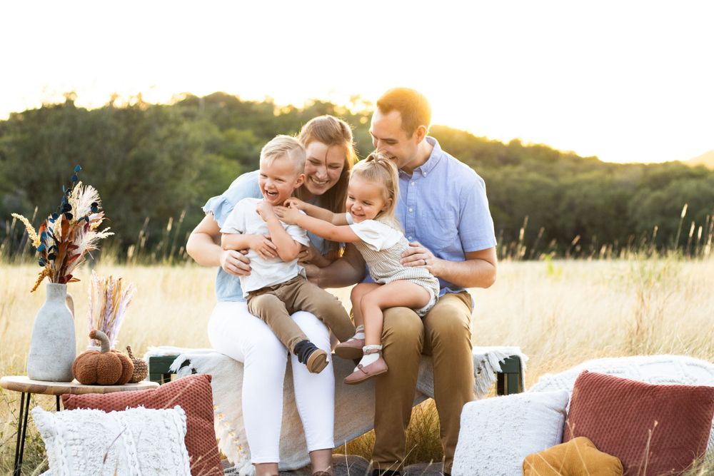Family enjoys a picnic together in a sunlit meadow at sunset.