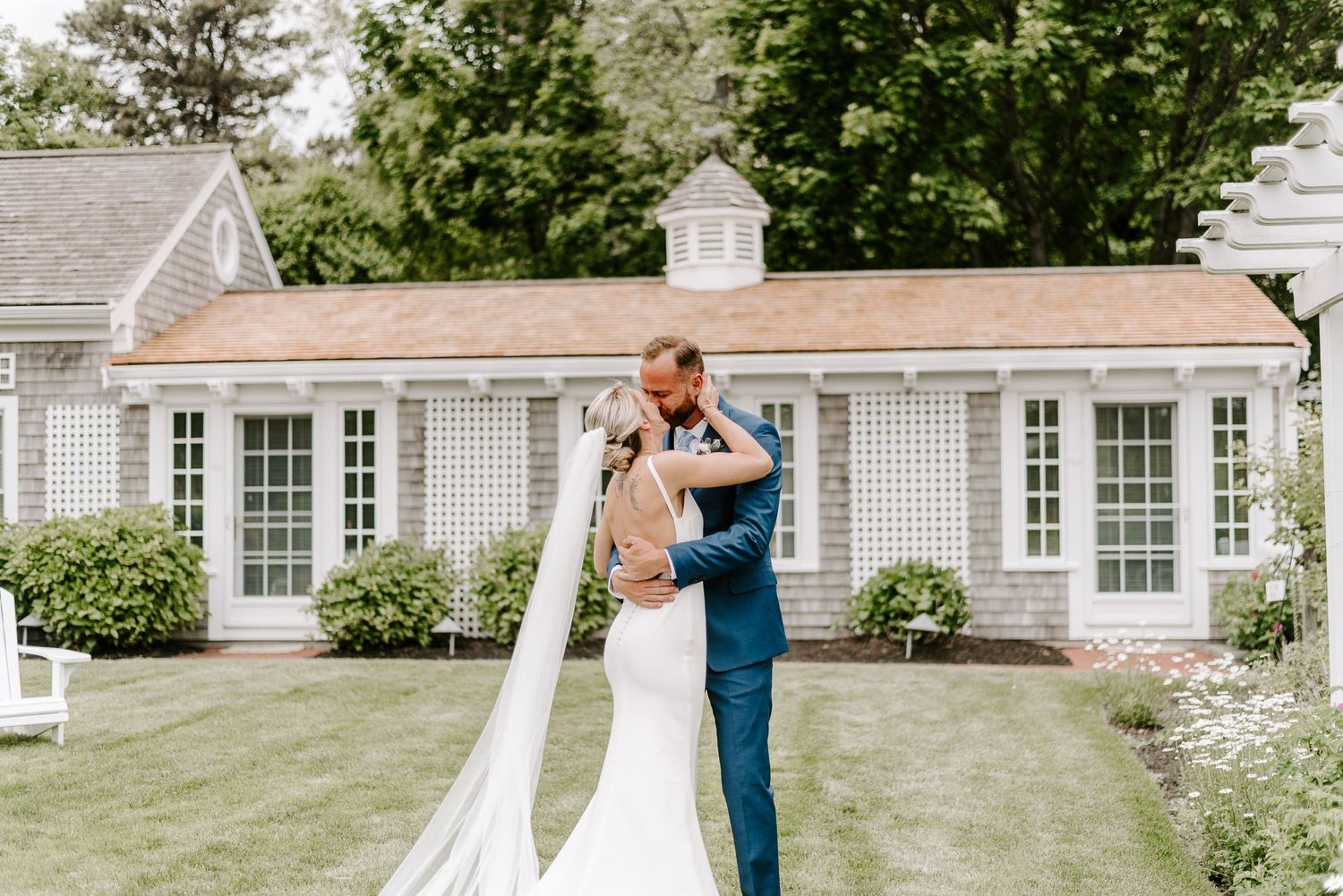 A touching moment captured between two people on a manicured lawn with a colonial house backdrop.