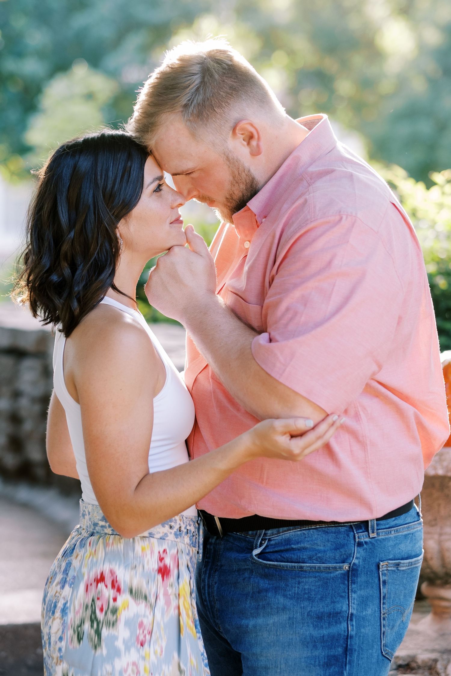 A tender romantic moment between a couple in coordinated pink and white outfits.