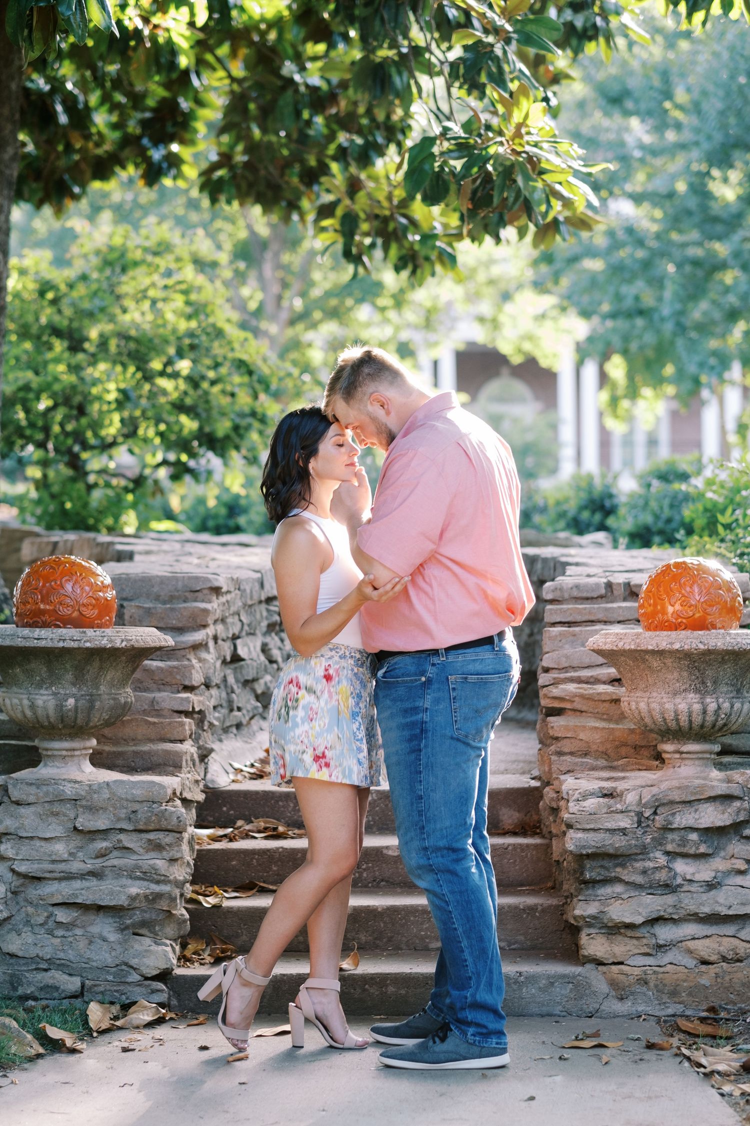 A romantic moment on stone steps decorated with orange pumpkins in a garden setting.