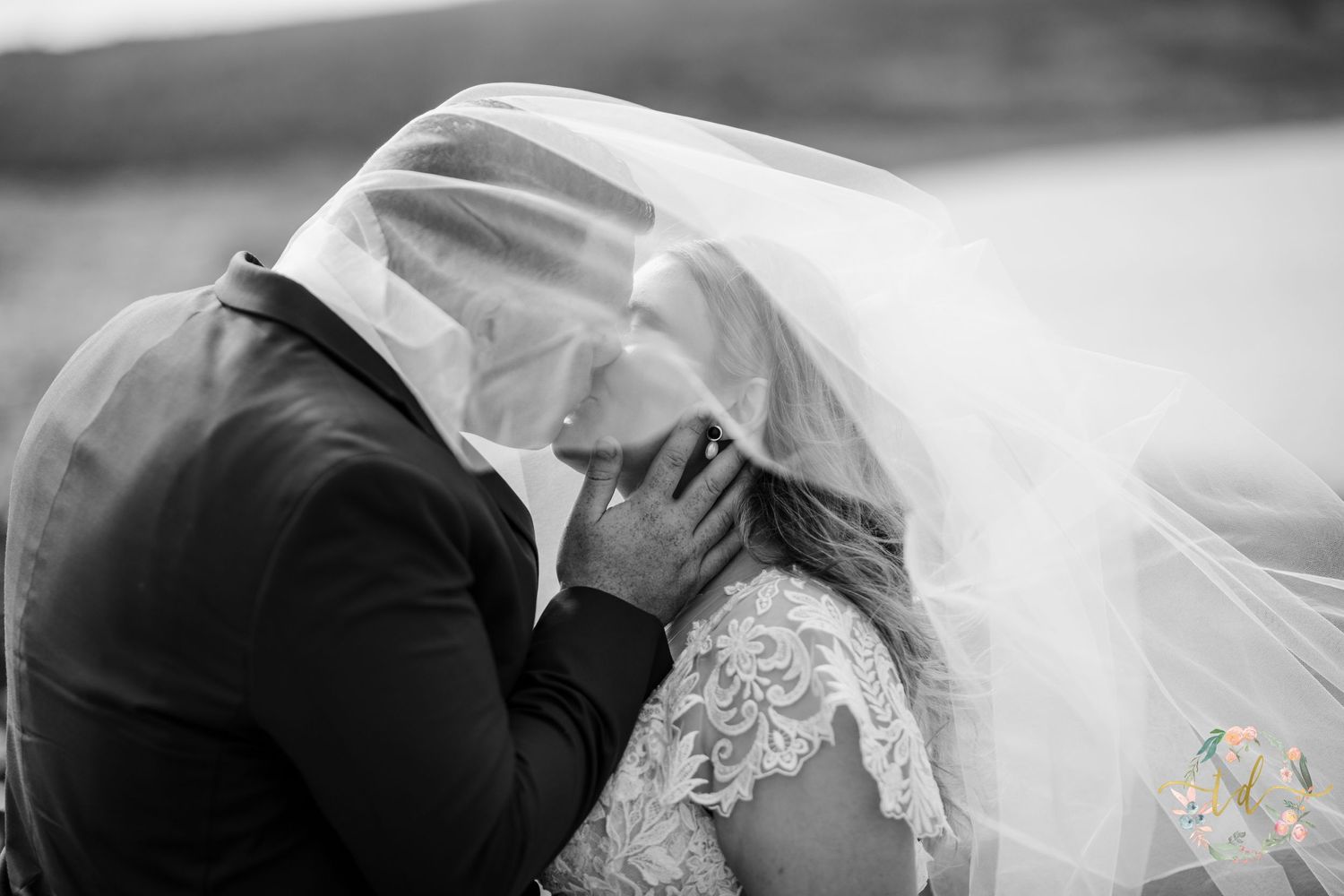 A romantic black and white moment between newlyweds under a flowing veil.