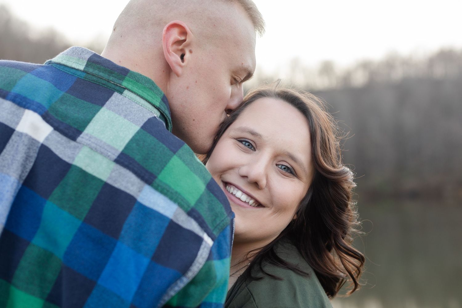 Close-up shots of a couple sharing tender moments by a tranquil lake at sunset.