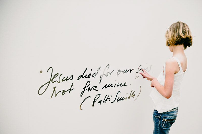 Someone writes a quote on a plain white wall with a black marker.