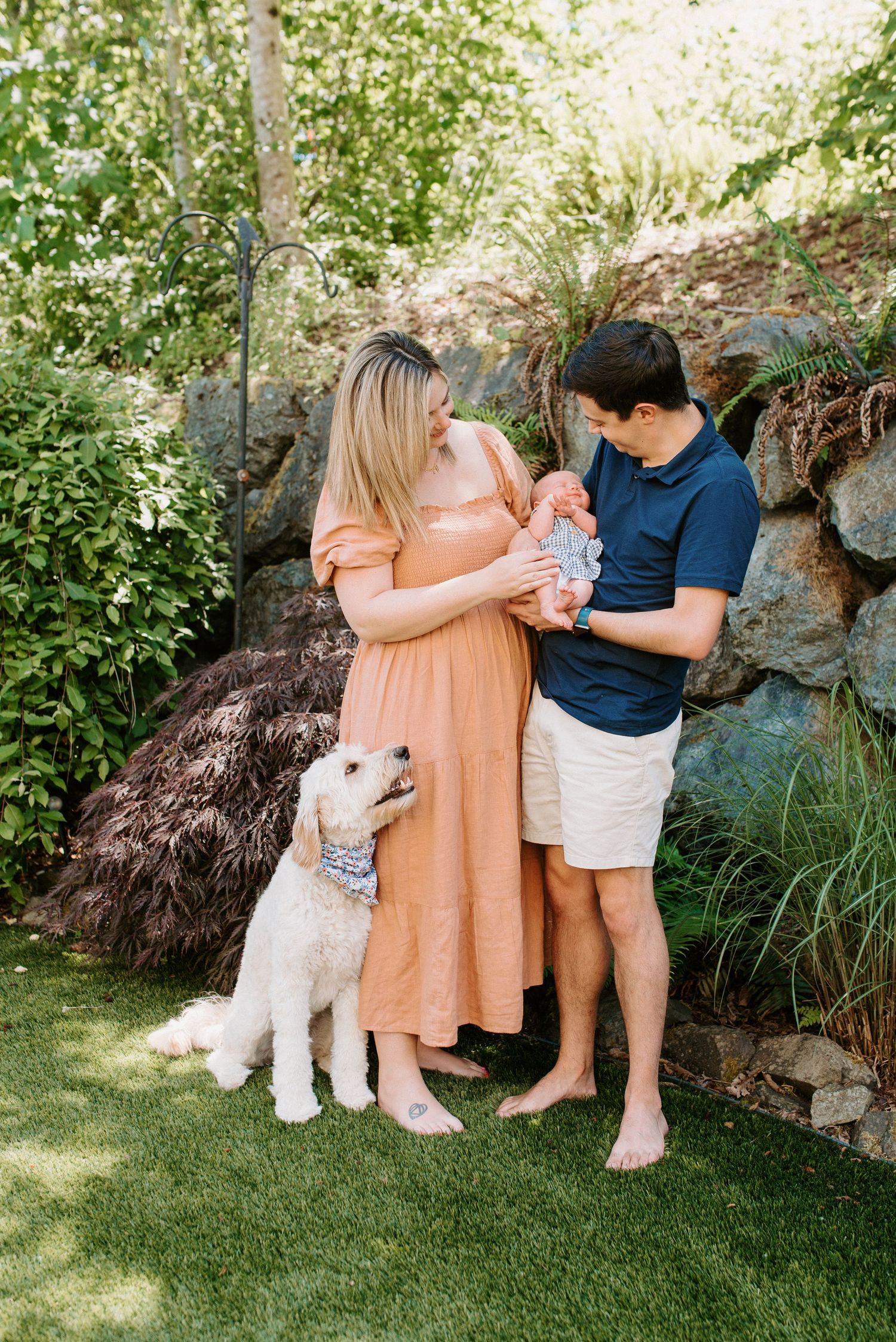 Family and white dog posing together in sunny garden setting.