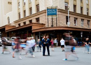Busy street scene outside historic Rydges hotel with motion blur of passing pedestrians.