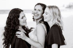 Black and white beach portrait of three friends sharing joyful moment.