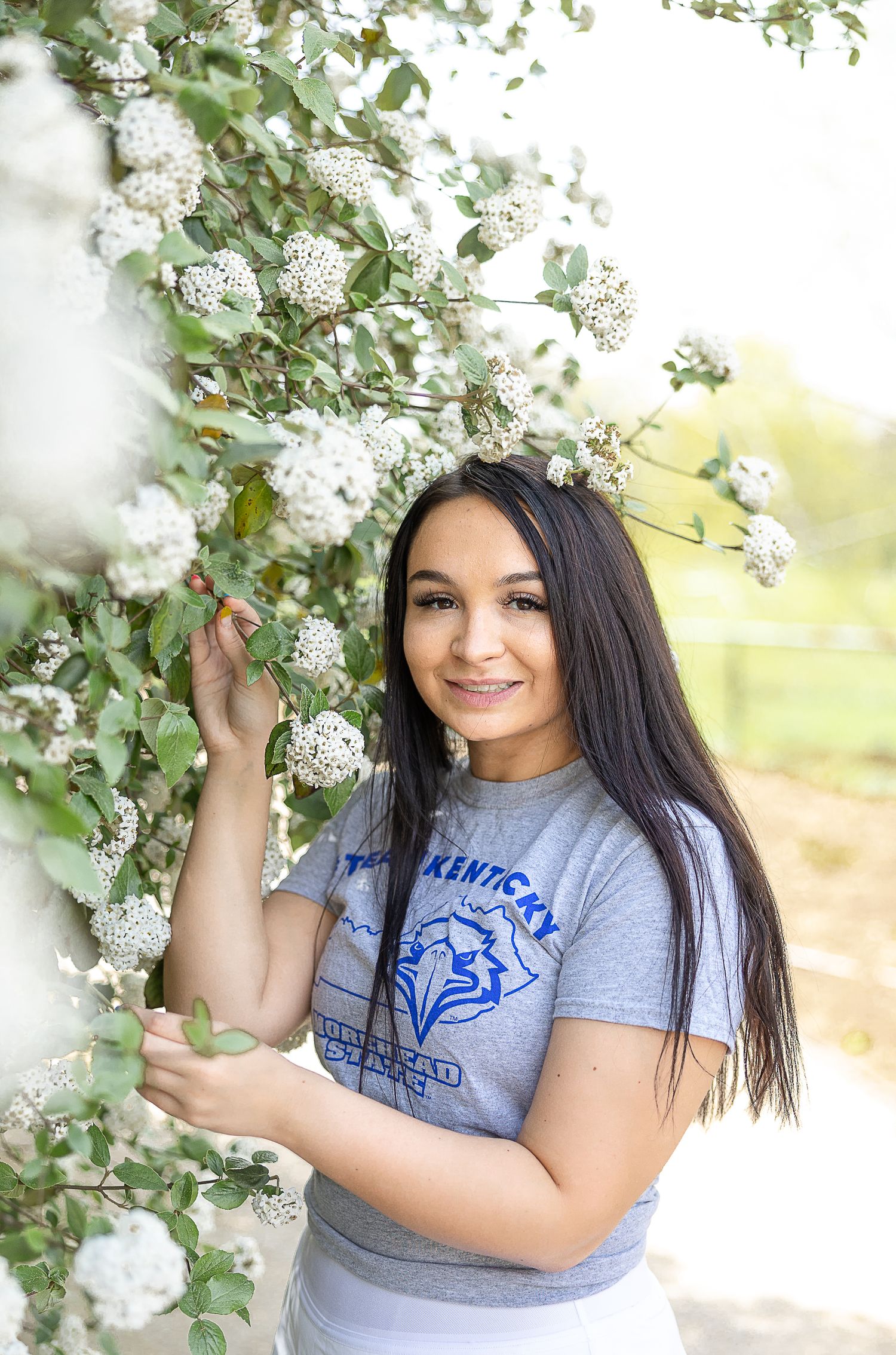 Spring portrait next to blooming white flowers wearing university spirit wear.