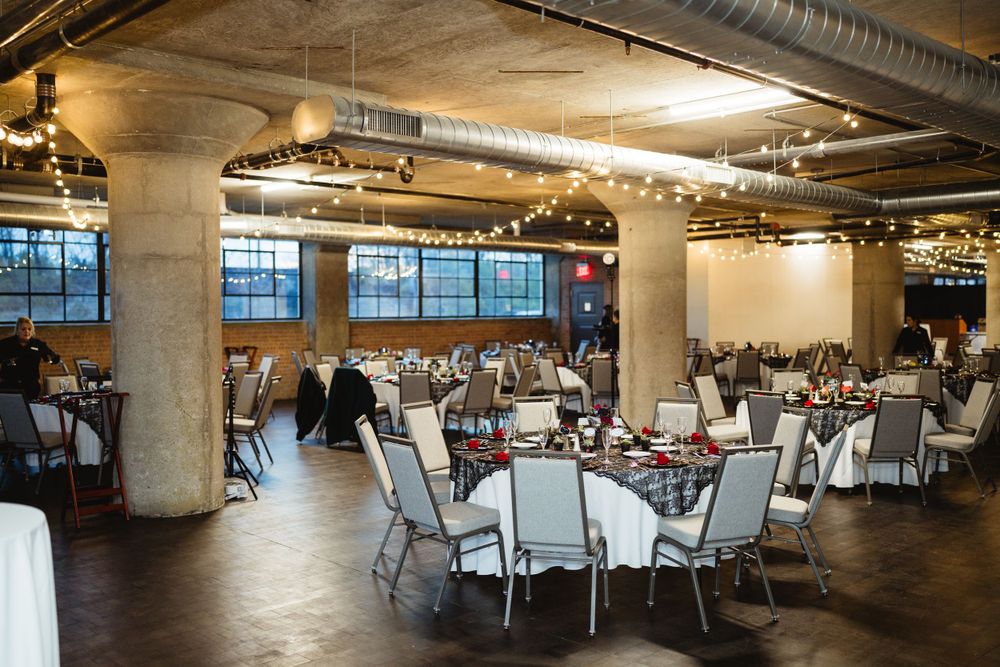 Industrial reception venue with round tables and exposed ceiling.