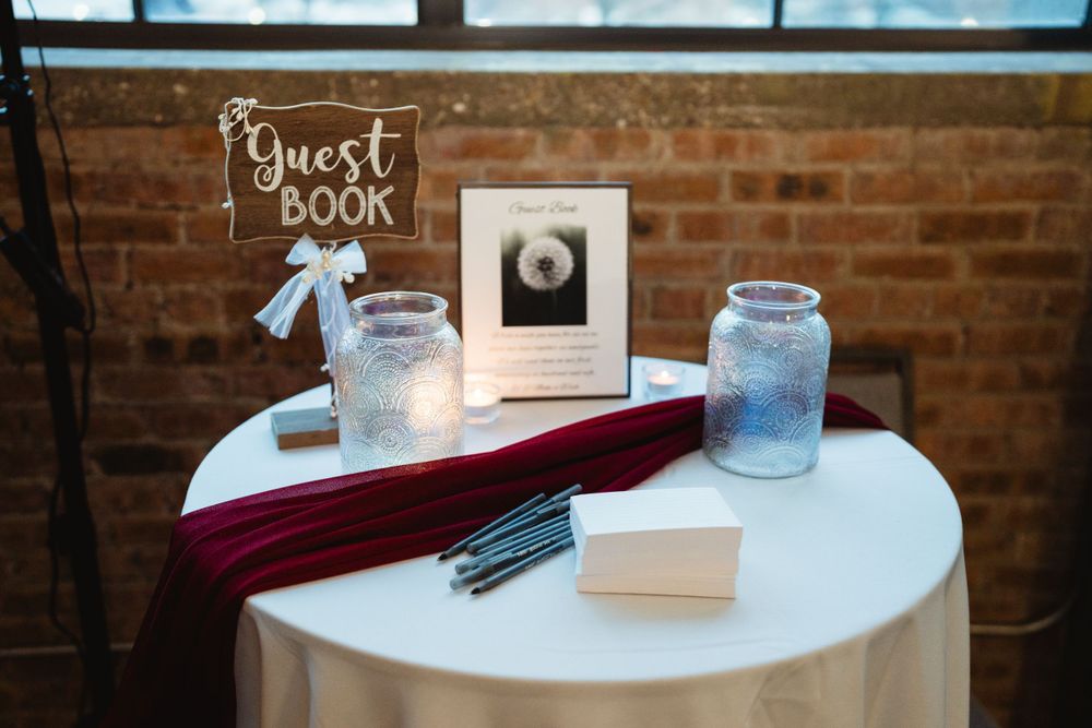 Guest book table setup with mason jars and burgundy velvet details.