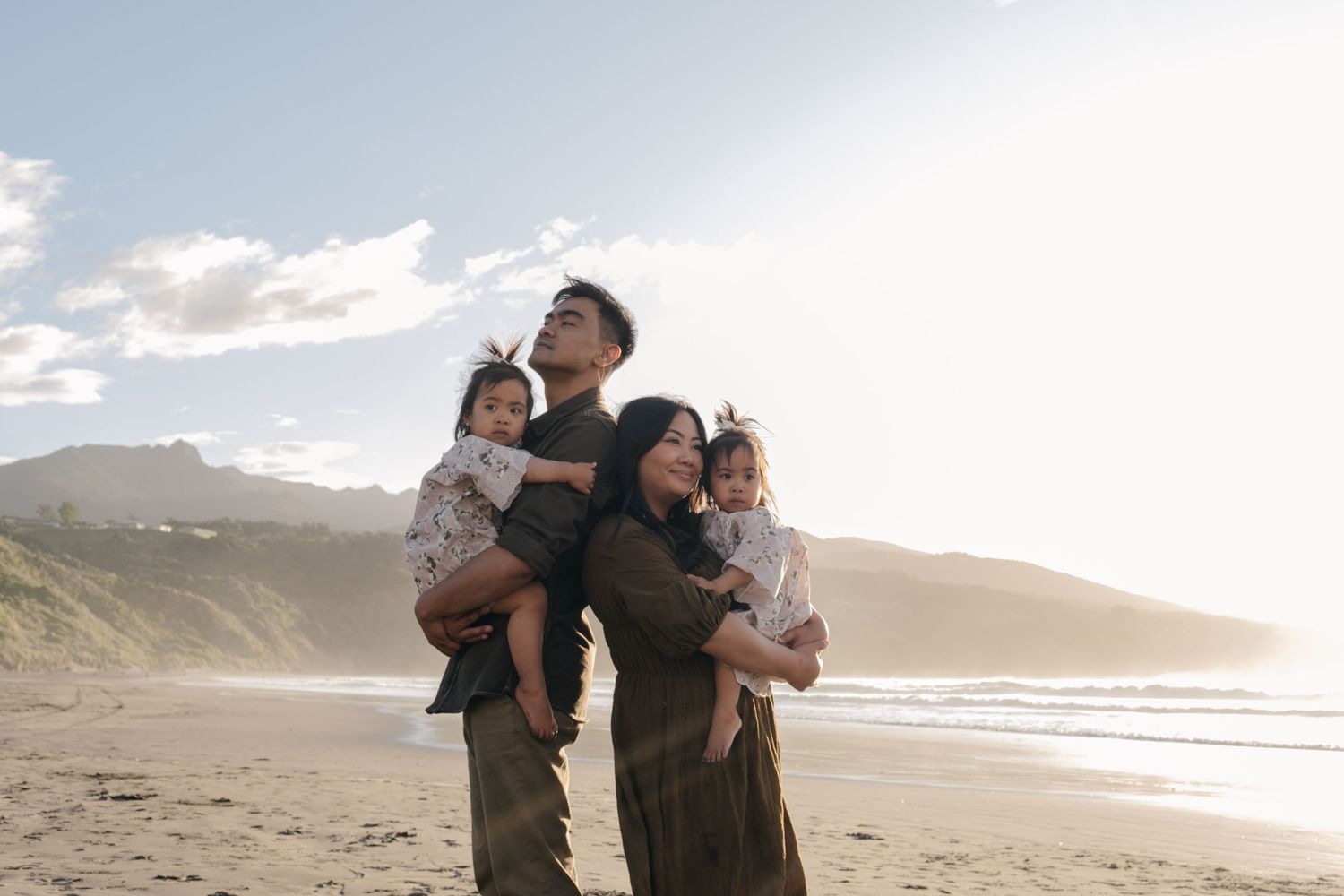 A joyful family embracing on a scenic beach at sunset.