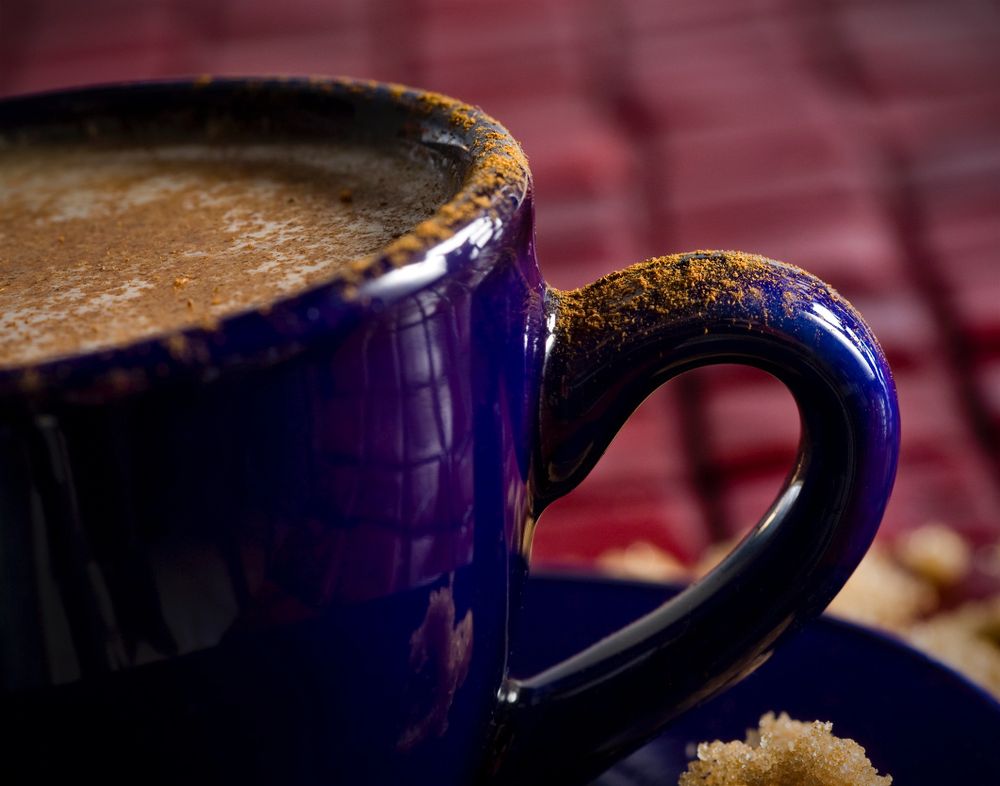 The rim of a blue, enameled latte mug is dusted with cinnamon.