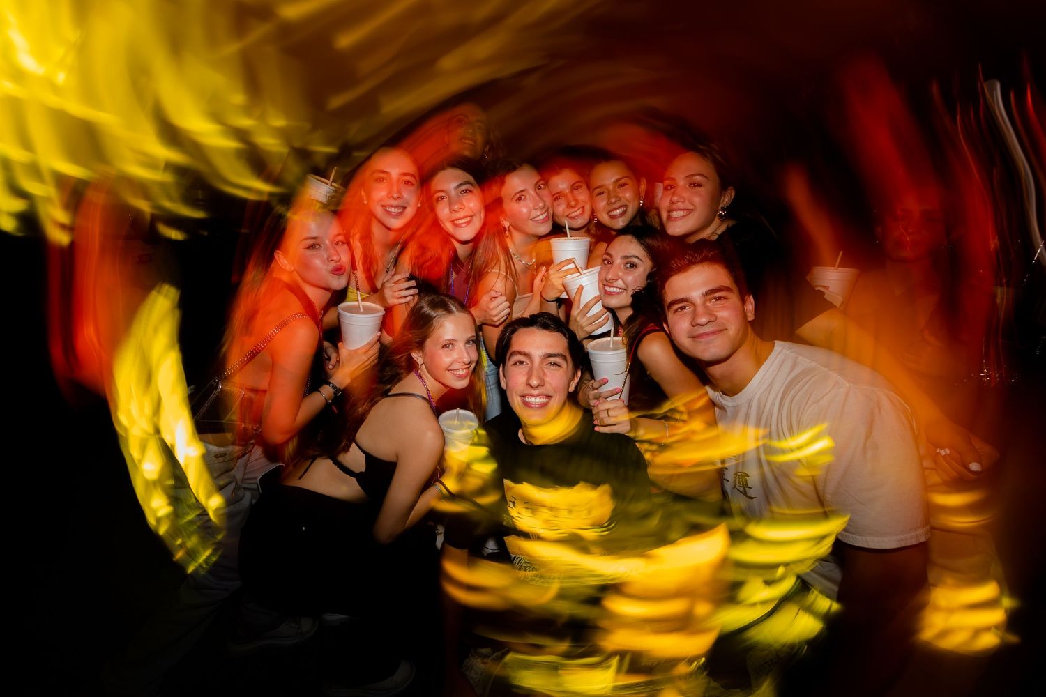 Group of young friends smiling and posing together at vibrant nightclub party.