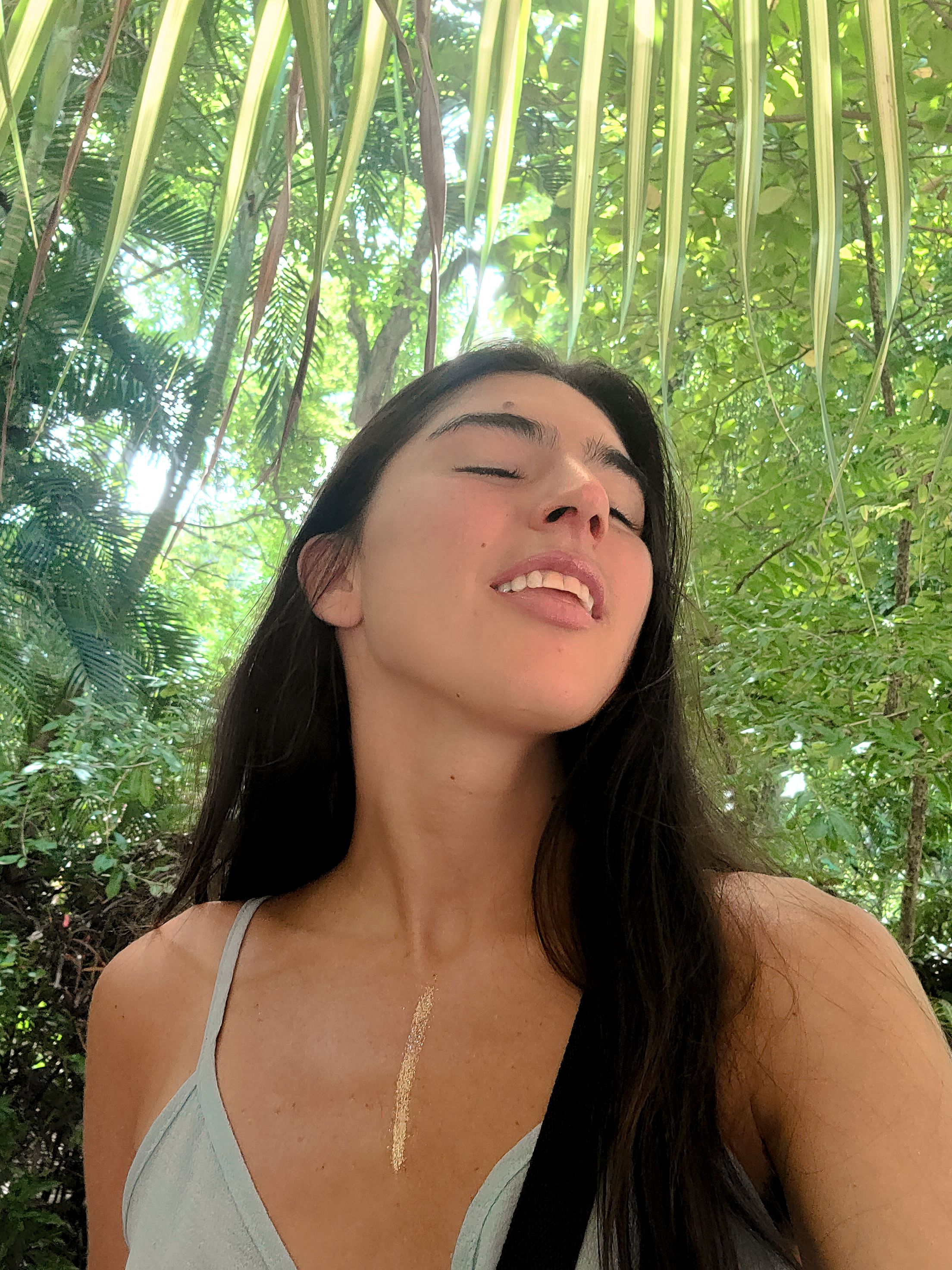 A serene moment captured beneath palm fronds in dappled sunlight.