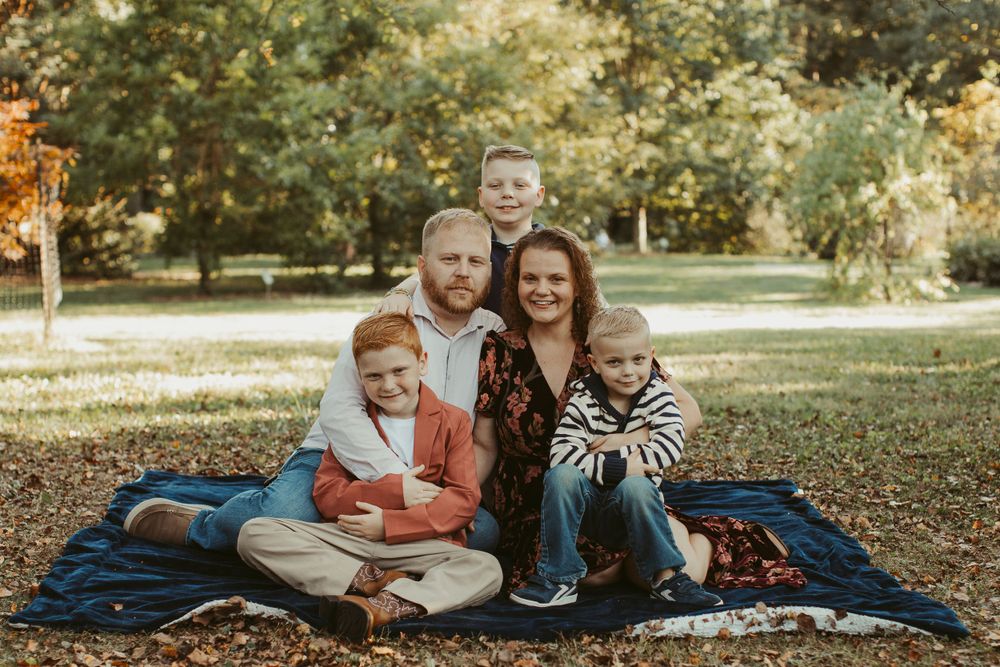 A family relaxing on a blue blanket during an autumn day in the park.