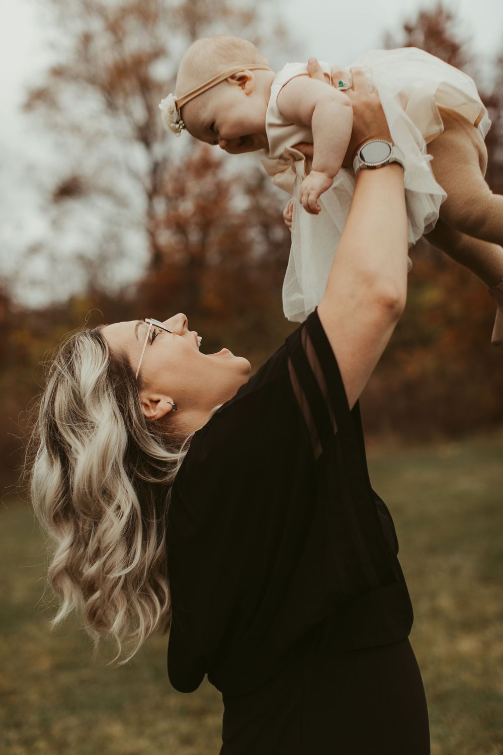 A joyful moment captured in autumn as someone lifts a small child in the air.