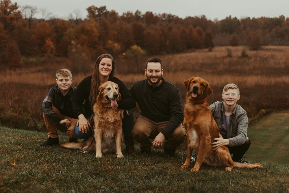 Family and their dogs relaxing together in a rustic fall setting.