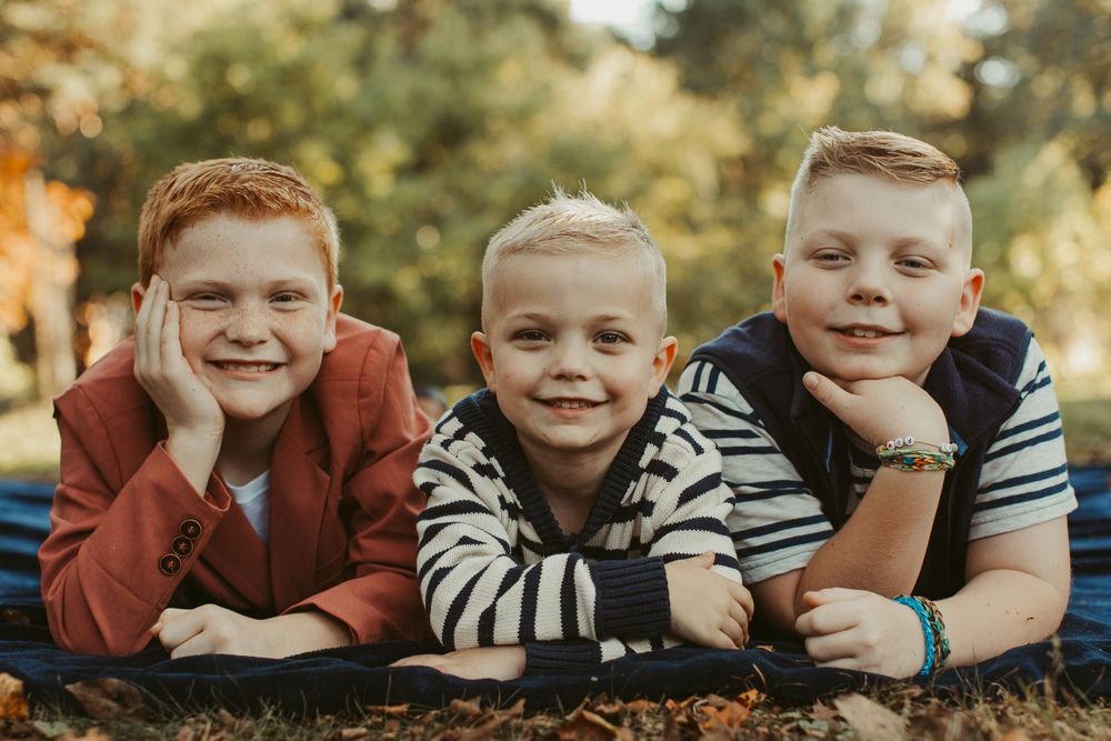 A row of smiling faces lying on grass during an autumn photoshoot.