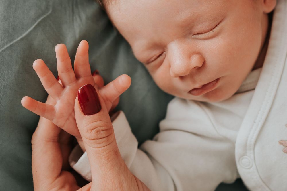 zbliżenie na buzię i rączkę noworodka trzymaną przez mamę - fotograf rodzinny Kraków