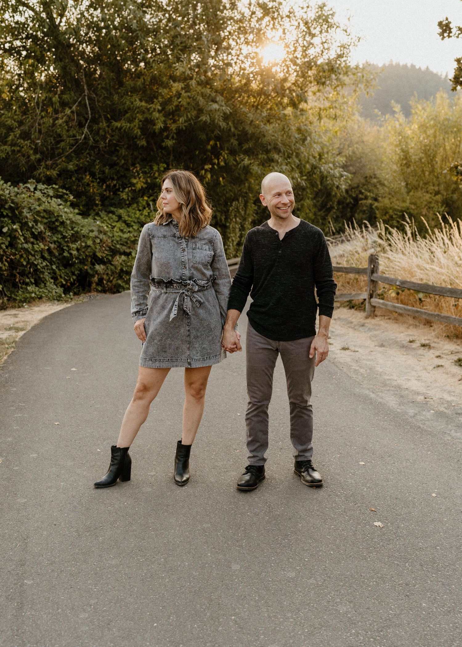 Megan and Dave Fleck in casual fall attire walks together on a paved path during golden hour with trees and sunlight in background.