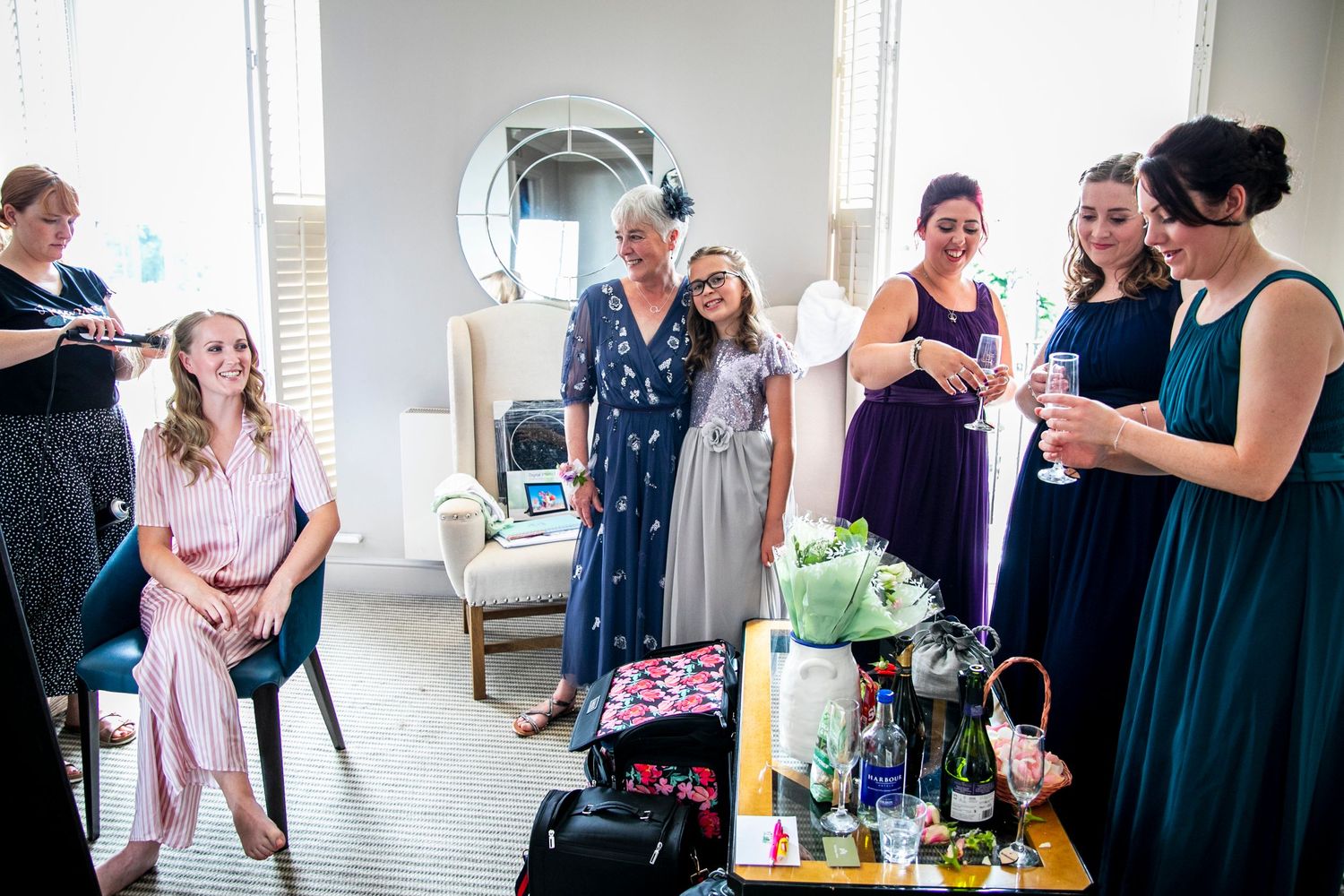 Wedding preparation scene with bridesmaids in navy dresses helping the bride get ready.