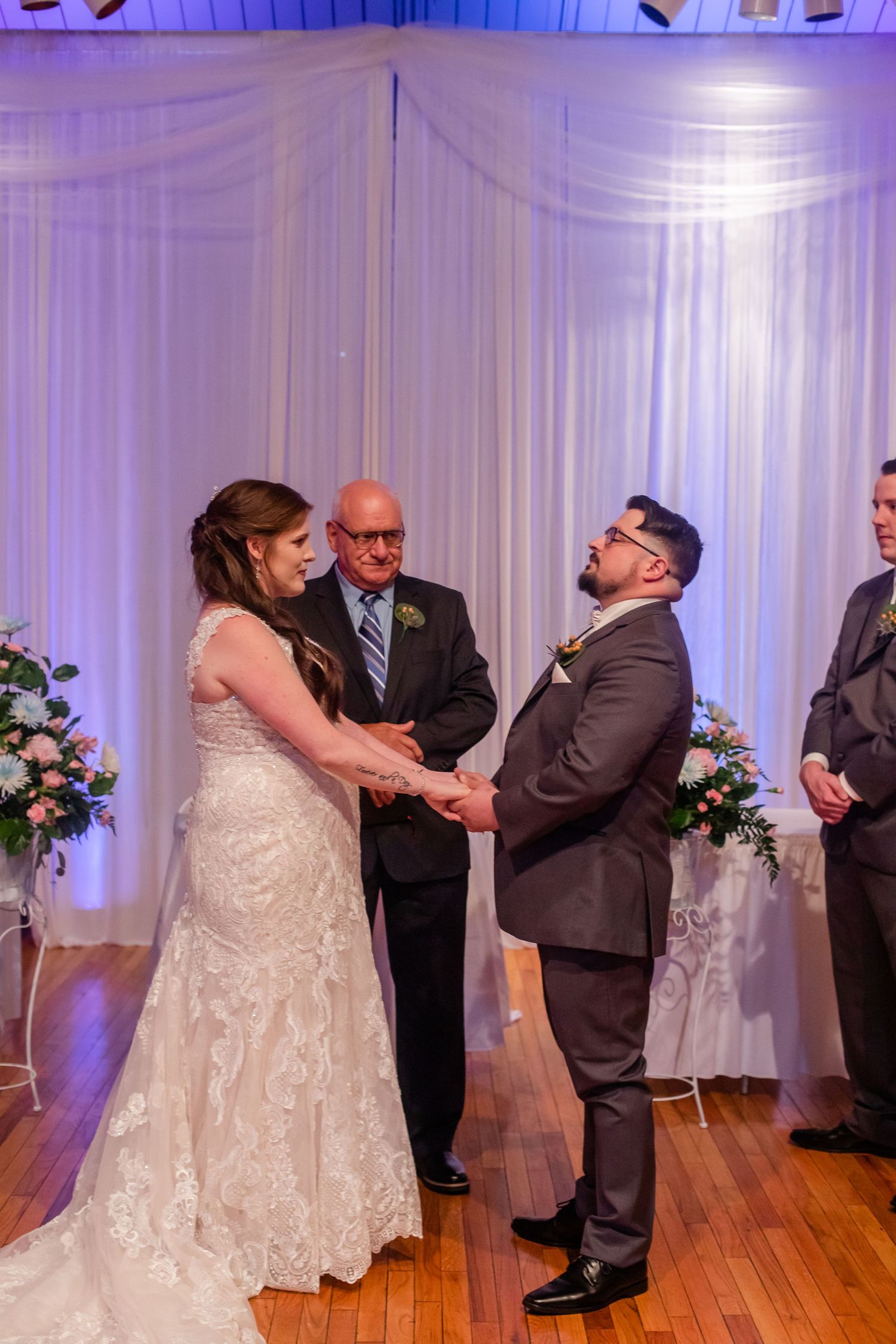 Wedding ceremony moments captured in sequence under purple lighting with white drape backdrop.