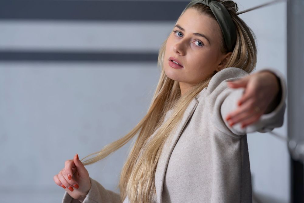 Person in light colored sweater poses against neutral background in studio setting.