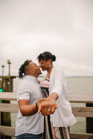 A romantic moment shared between a couple on a waterfront dock at sunset.