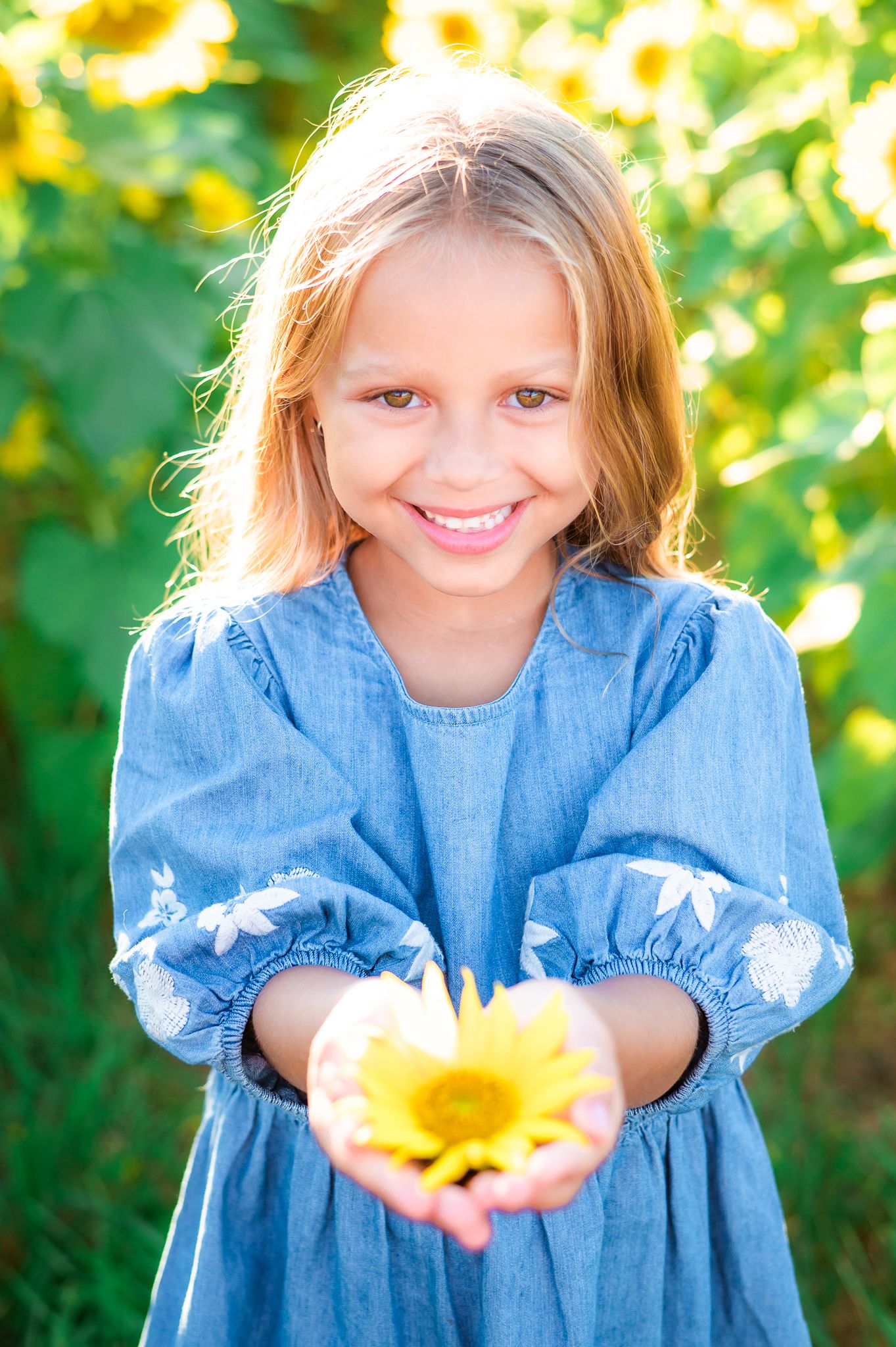 Bright smiling girl holding sunflower in Frederick Maryland